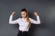© Viorel - Confident business woman clenching her fists is confident about winning the business project. Grey background.