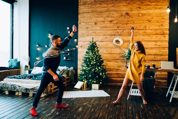 Wall Mural - Funny young couple messing around with Christmas serpentine