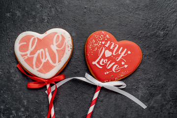 Wall Mural - Two heart shaped cookies on sticks for valentine's day on a stone background with copy space for your text