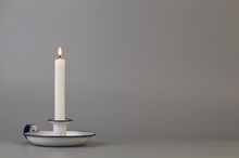 White Candle In An Old White Candlestick On A Gray Background Close-up.