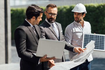 Wall Mural - Hipster business man and Office building owner and energy engineer plan a project to build a solar panel for the building under construction. clean and green alternative energy concept.