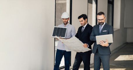 Wall Mural - Hipster business man and Office building owner and energy engineer plan a project to build a solar panel for the building under construction. clean and green alternative energy concept.