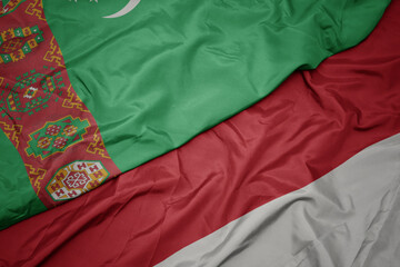 waving colorful flag of indonesia and national flag of turkmenistan.