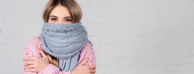 Young woman in sweater and scarf suffering from cold on white background, banner