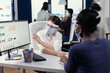 © DC Studio - Coworkers wearing face mask checking corporate statistics during coronavirus. Multiethnic team working in company with new normal respecting social distance.