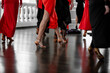Beautiful  woman legs dancing tango wearing black and red dresses, unrecognizable, blurred background