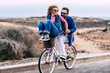 © simona - Joyful love friendship concept - happy adult caucasian, couple having fun with bicycle in outdoor leisure activity. concept of active playful people with bike during vacation - everyday joy lifestyle
