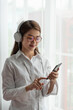 © surachetkhamsuk - Young Asian woman enjoy listening to music with headphones while holding mobile phone, happy and relaxing time