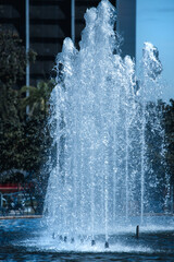 Splashes of fountain water against city architecture in a sunny day.  Urban landscapes.