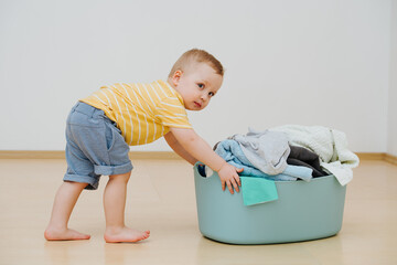 Little boy pushes basket with clean laundry after washing. High quality photo