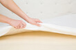 © fotoduets - Young adult woman hands opening white cover and showing yellow rubber foam inside orthopedic mattress. Closeup.