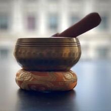 Chiming Brass Meditation Bowl With Wooden Hammer On A Small Orange And Gold Cushion. Shallow Focus.