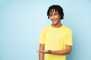 Sticker - Young african american man isolated on blue background presenting an idea while looking smiling towards