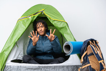 young african american man inside a camping green tent counting eight with fingers