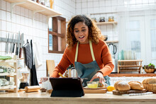Young Afican American Woman Learning Online  Cooking Class Via Tablet Computer In Kitchen At Home