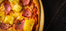 Just Baked Hawaiian Pizza With Freshly Chopped Pineapple And Ham On The Rustic Wooden Background. Selective Focus.