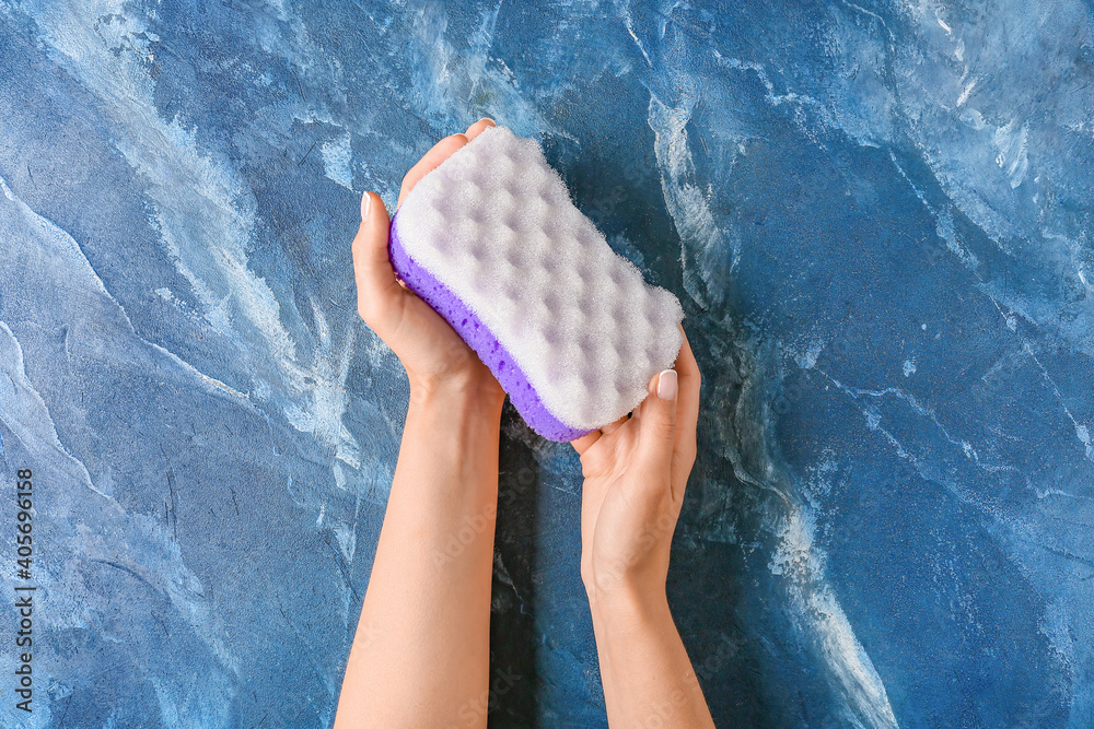 Female hands with bath sponge on color background