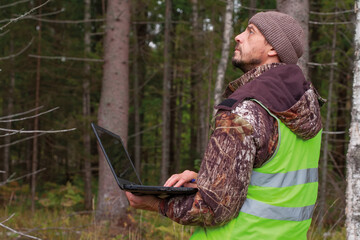 Wall Mural - Ecologist works in the forest on a computer. The forest engineer oversees the development of the forest. Forestry concept.