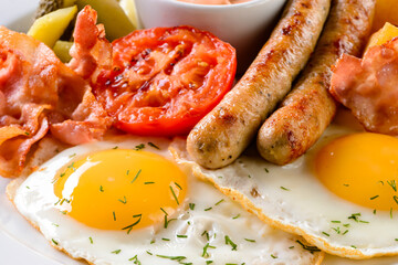 Wall Mural - Two fried eggs serve with roasted vegetables and bacon, closeup fried egg with vegetables for English breakfast