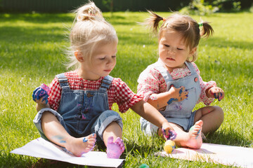 Wall Mural - Two little girls sisters paint with finger paints