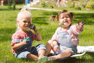 Wall Mural - Two little girls sisters paint with finger paints