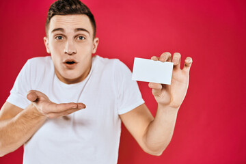 A man in a white T-shirt with a business card in his hands emotions red background