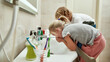 Two cute little kids, boy and girl rinsing mouth after brushing teeth in the bathroom