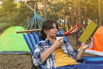 Poster - Woman with book resting in comfortable hammock outdoors