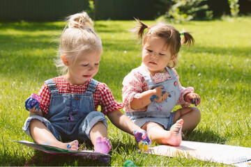 Wall Mural - Two little girls sisters paint with finger paints