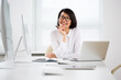 © chagin - Asian business woman smiling at camera in an office