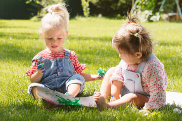 Two little girls sisters paint with finger paints