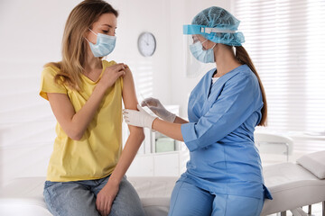 Wall Mural - Doctor vaccinating young woman against Covid-19 in clinic