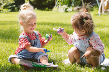 Wall Mural - Two little girls sisters paint with finger paints