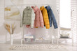 © New Africa - Different warm jackets on rack in stylish room interior