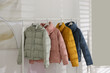 © New Africa - Different warm jackets hanging on rack indoors