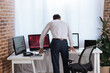 © LIGHTFIELD STUDIOS - Back view of forex businessman standing near computers with charts in office
