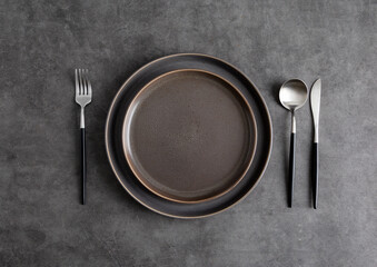 Empty plate with tableware at gray background. Top view, flat lay, concept of elegance dark table setting