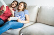 © PhotoAlto - Young couple talking with each other on sofa in their new house