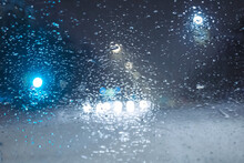 Water Droplets From Melting Snow During A Snowfall On The Windshield Of A Car. Blurred Image.