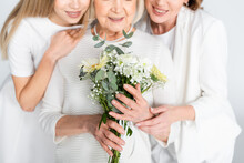 Cropped View Of Pleased Senior Woman Smiling While Holding Flowers Near Daughter And Granddaughter Isolated On White