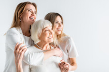 Three Generation Of Positive Women Smiling While Hugging Isolated On White
