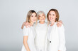 © LIGHTFIELD STUDIOS - three generation of cheerful women smiling while looking at camera and hugging isolated on grey