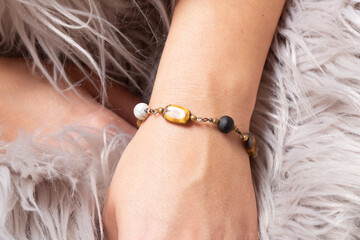 Female hand wrist wearing brass golden bracelet with various mineral stones