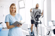 © prostooleh - A woman is a physiotherapist. A man is using a spin bike. The patient is having a treatment.