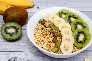 Wall Mural - Bowl of oatmeal porridge with banana, kiwi and  pumpkin seeds. healthy food for Breakfast