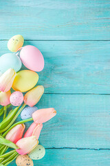 Canvas Print - Spring and Easter holiday background with tulip flowers, colorful pastel eggs on blue table top view. Happy Easter greeting card.