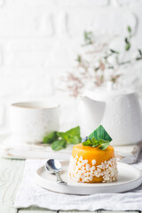 Wall Mural - Piece of mango mousse cake on plate over white wooden table.