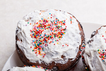 Wall Mural - Top view of four freshly baked Easter cakes close-up with traditional confectionery decoration - frozen white icing sprinkled with multicolored round confetti, a treat for a christian church holiday.