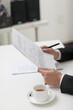 © eastfenceimage - Portrait of young businessman at desk holding documents and pen
