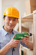 © eastfenceimage - Portrait of young workman using electric drill in office,close-up